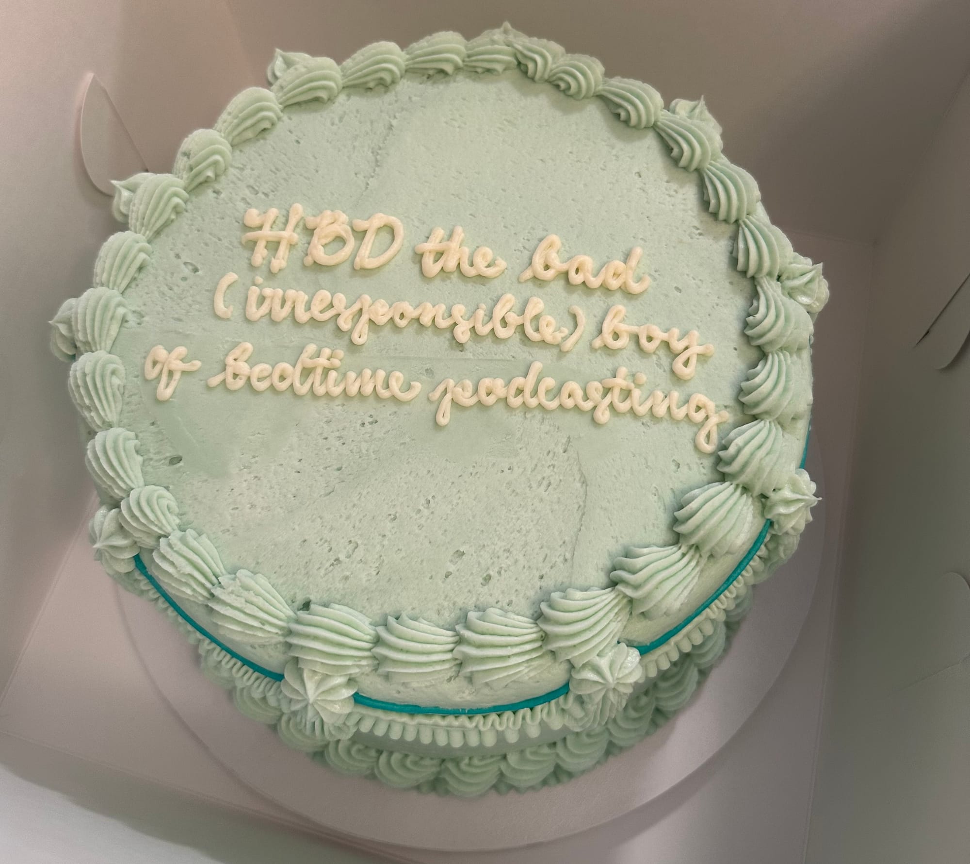 Sea foam green frosted birthday cake reading, in cursive: "HBD the bad (irresponsible) boy for bedtime podcasting."