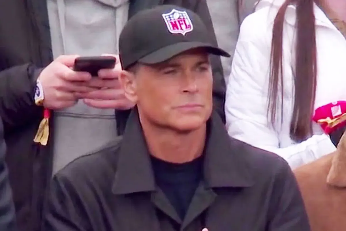 Rob Lowe in his famous NFL hat at a football game.